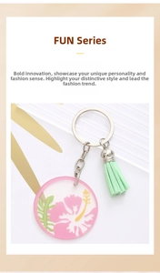Detail of acrylic floral keychain with pink hibiscus print and green tassel accent