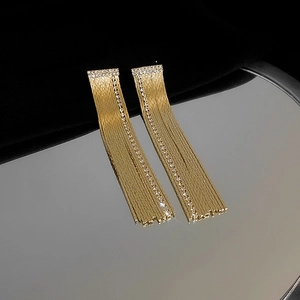 Detail of long gold tassel earrings featuring vertical sparkling zircon rows on velvet