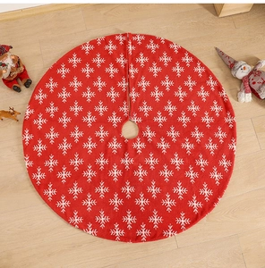 Detail of red knitted Christmas tree skirt with white snowflake patterns and festive decor