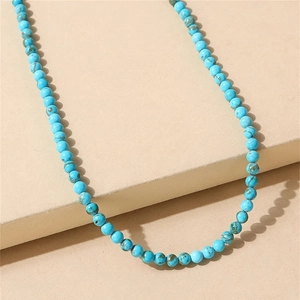 Close-up of turquoise bead necklace with natural matrix textures on a beige display