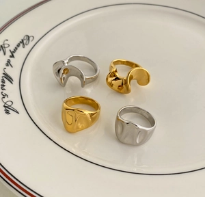 Detail shot of four gold and silver irregular wavy rings displayed on a ceramic dish