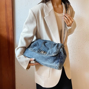 Vintage blue denim tote bag with chain strap shown on model in minimalist setting