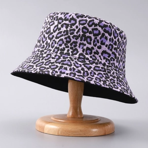 Detailed close-up of a purple leopard print bucket hat on a wooden hat stand