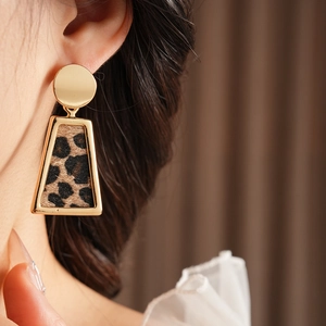 Gros plan de boucles d'oreilles dorées géométriques avec texture léopard sur le lobe