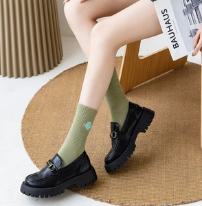 Detail of green knit socks with planet embroidery paired with black platform loafers