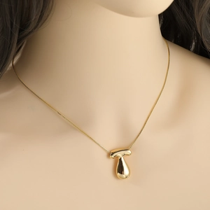 Minimalist gold alphabet pendant necklace with modern abstract design on model