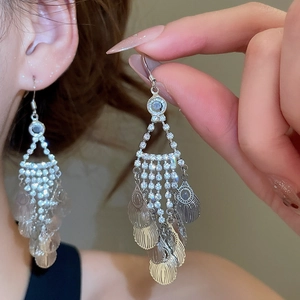 Detailed view of silver leaf tassel earrings with sparkling rhinestones worn on ear