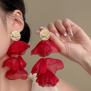 Detailed shot of red pleated chiffon flower earrings with textured gold metal studs