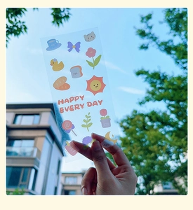 Transparent cartoon stickers with cat and sun motifs held against a blue sky background