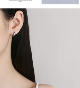Close-up of small 925 sterling silver hoop earrings with white zircon on a female ear