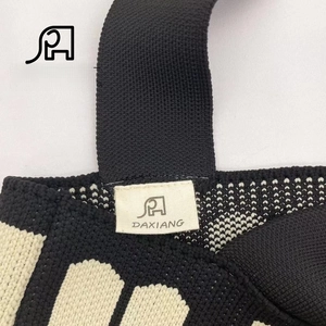 Detailed view of the woven fabric texture and stitched brand label on a knit tote bag