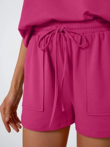 Detail of magenta shorts featuring an elastic drawstring waistband and functional side pockets