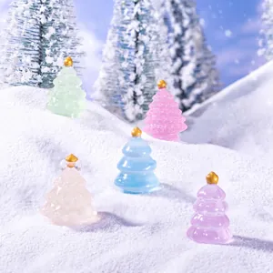 Miniature macaron colored luminous Christmas trees on snow for DIY festive decoration