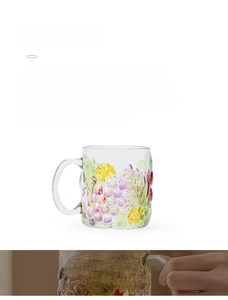 Detail view of hand-painted grape and floral patterns on a clear glass mug with handle