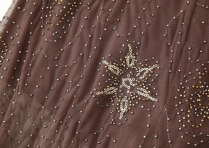 Vue macro détaillée du tissu en tulle marron avec broderies de paillettes argentées et dorées
