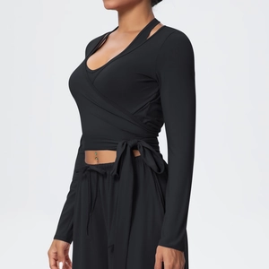 Detail of black wrap-style yoga top with cross-front design and waist tie ribbon