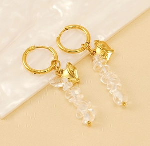 Detail of golden fox head hoop earrings with natural white stones on a wavy tray