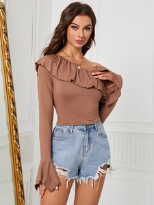 Top de punto marrón con hombros descubiertos y volantes con pantalones cortos vaqueros