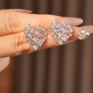 Close-up of heart-shaped silver earrings with sparkling zircon and rhinestone settings