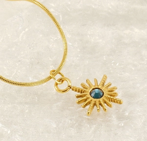 Macro shot of gold sunburst tarot pendant with a faceted deep blue gemstone center