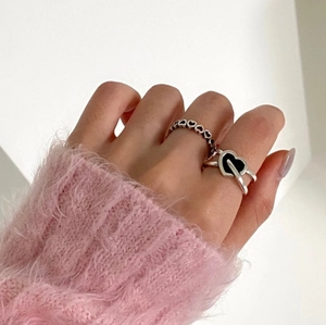 Close-up of S925 silver heart rings with black heart stones on model wearing pink sweater