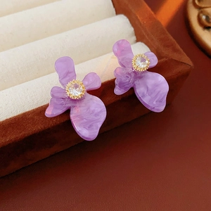Détail de boucles d'oreilles fleur en résine violette avec texture marbre et zircon