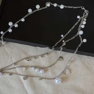 Detail of silver layered waist chain with white pearls and a delicate shell pendant