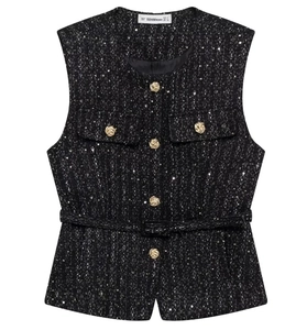 Close-up of black tweed vest texture with sequins, gold buttons, and belted waist detail