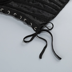 Detail of black corset top featuring satin fabric, metal eyelets, and criss-cross lacing