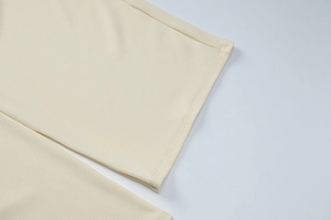 Detailed macro view of cream rib-knit fabric texture and high-quality stitching seams