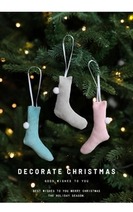 Cozy knitted Christmas stockings with pom-poms on tree with warm holiday lights