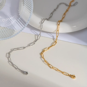 Polished gold and silver stainless steel paperclip chain anklets on minimalist background