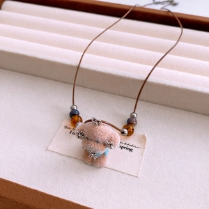 Detail of plush puppy pendant on beaded chain inside an elegant jewelry display box
