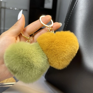 Close-up of yellow and green heart-shaped plush keychains with golden metal rings