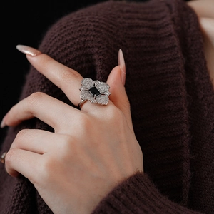 Macro shot of silver ring featuring a dark square gem and zircon floral design on model