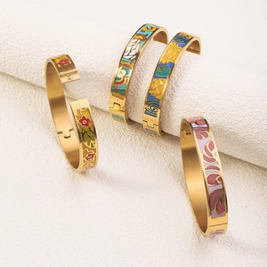 Detailed macro view of four 18K gold-plated stainless steel bangles with colorful enamel art