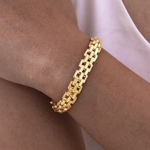 Detail shot of a double-row golden stainless steel chain bracelet worn on a wrist