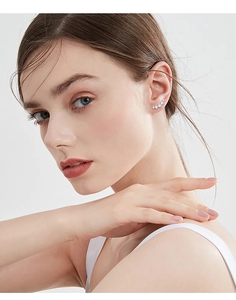 Close-up of curved 925 silver stud earrings with moissanite stones on a female ear