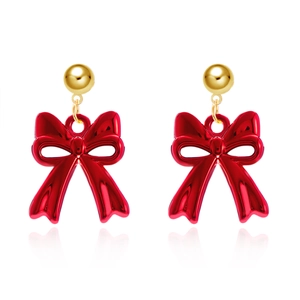 Detailed view of red bow earrings with gold spherical studs on a reflective white surface