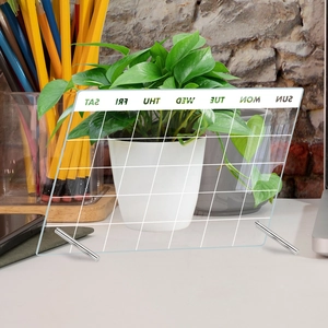 Macro view of transparent acrylic weekly calendar board with metal stand on desk
