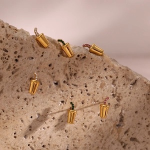 Close-up of gold soda cup earrings with colorful inlaid stones on a textured stone base