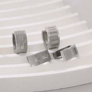 Close-up of brushed titanium steel hoop earrings with cross and Roman numerals engraving