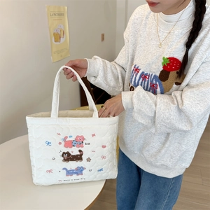 Close-up of quilted white tote bag featuring cute cat and star embroidery detail