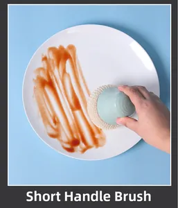 Short handle kitchen cleaning brush scrubbing red sauce off a white ceramic plate