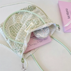 Détail du sac en dentelle vert clair avec broderie florale et bandoulière en perles