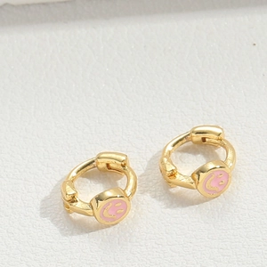 Detailed macro shot of golden star earrings featuring pink smiley face oil drip craftsmanship