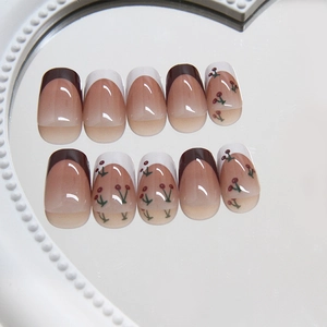 French tip press-on nails with cherry patterns on a pearl-rimmed mirror display
