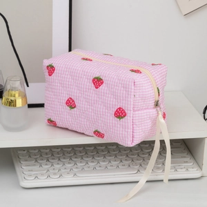 Close-up of strawberry print makeup bag with pink checkered fabric and ribbon zipper