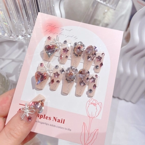 Detail of long coffin press-on nails with sparkling heart diamonds and silver bows