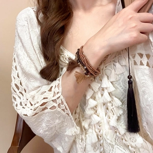 Macro shot of multi-layered bohemian beaded bracelet with tassel and bronze accents